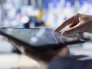 Primer plano de una mano controlando una tablet para gestionar unas aduanas inteligentes.