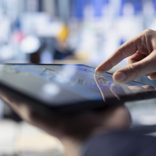 Primer plano de una mano controlando una tablet para gestionar unas aduanas inteligentes.